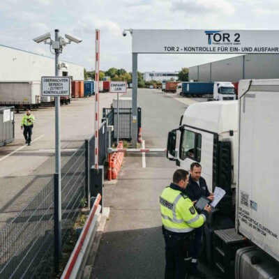 Ladungsdiebstahl im Straßengüterverkehr, Schutz vor Ladungsdiebstahl, Torkontrolle auf einem Logistikgelände, Ausfahrtkontrolle eines LKW, Werkschutz für Logistikstandorte, Sicherheitskontrolle eines LKW am Werkstor, bewachter Logistikstandort gegen Ladungsdiebstahl, Kontrolle von LKW und Ladung am Werkstor
